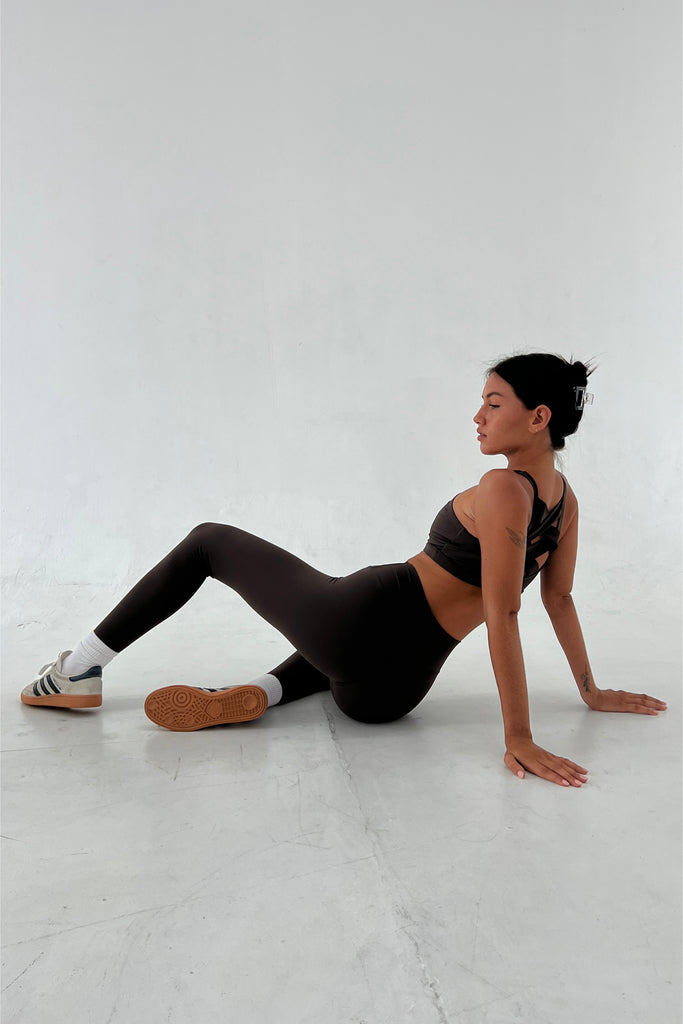 Mesmerizing in her poise, a woman clad in a bra and legging set exhibits flawless flexibility as she leans back, her elegant leggings offering a seamless and polished appearance.